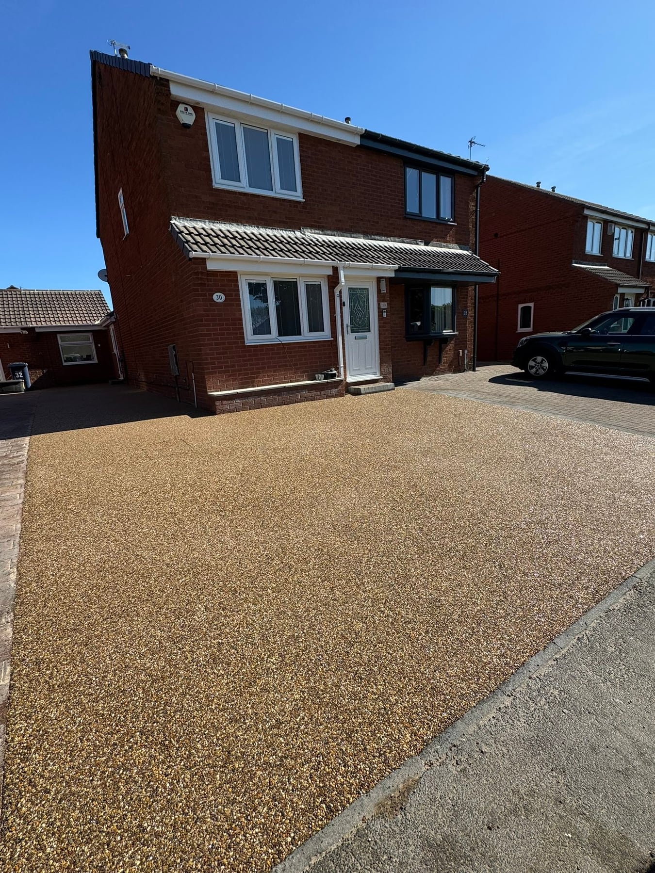 Golden resin-bound driveway outside a red brick home