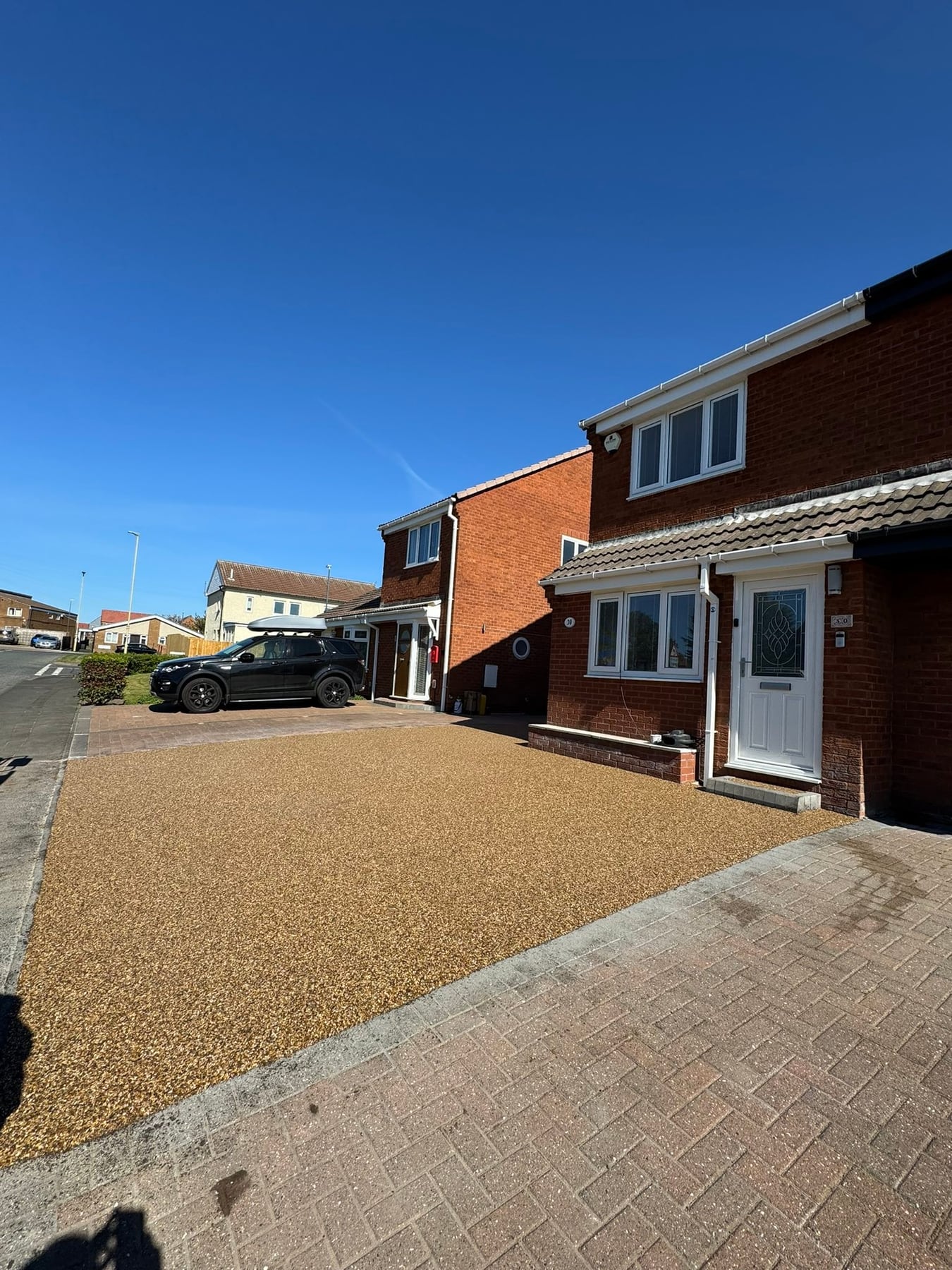 Sunlit resin driveway in a residential cul-de-sac