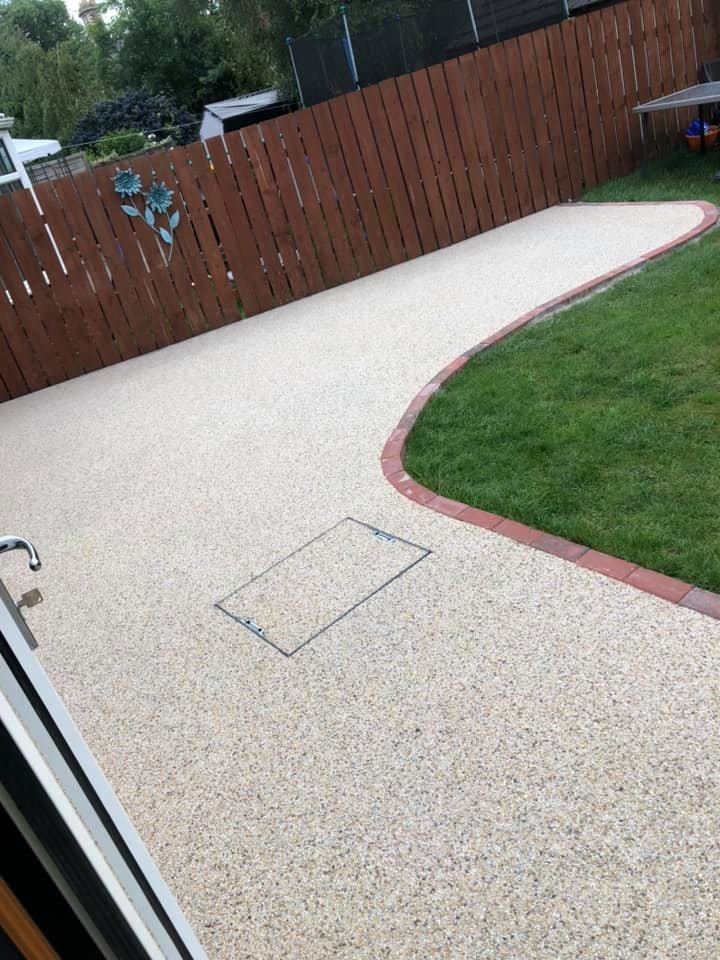 Pale resin driveway wrapping a lawn edge
