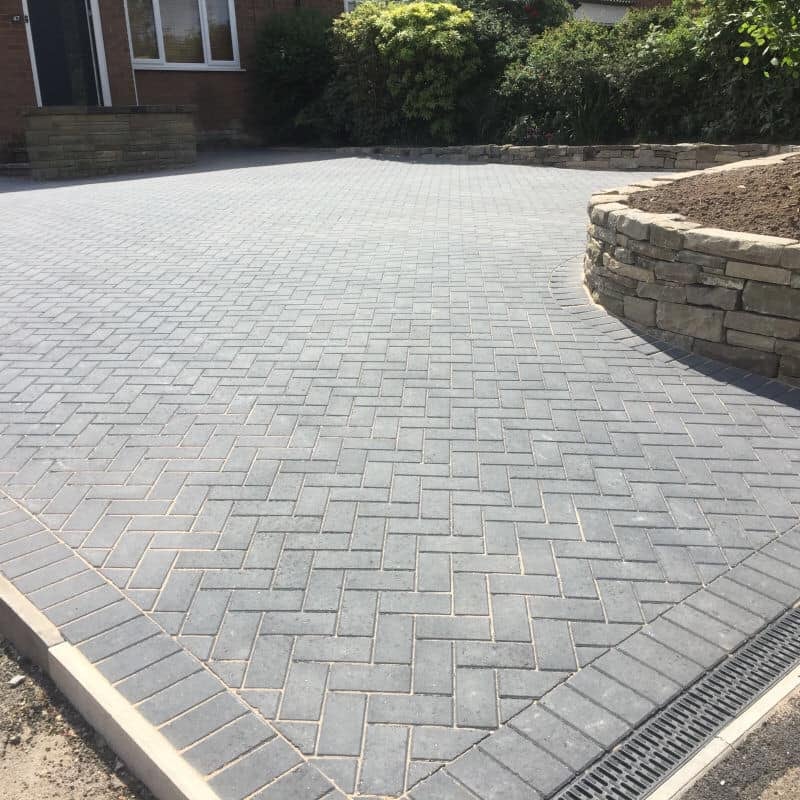 Light block-paved driveway with curved retaining wall