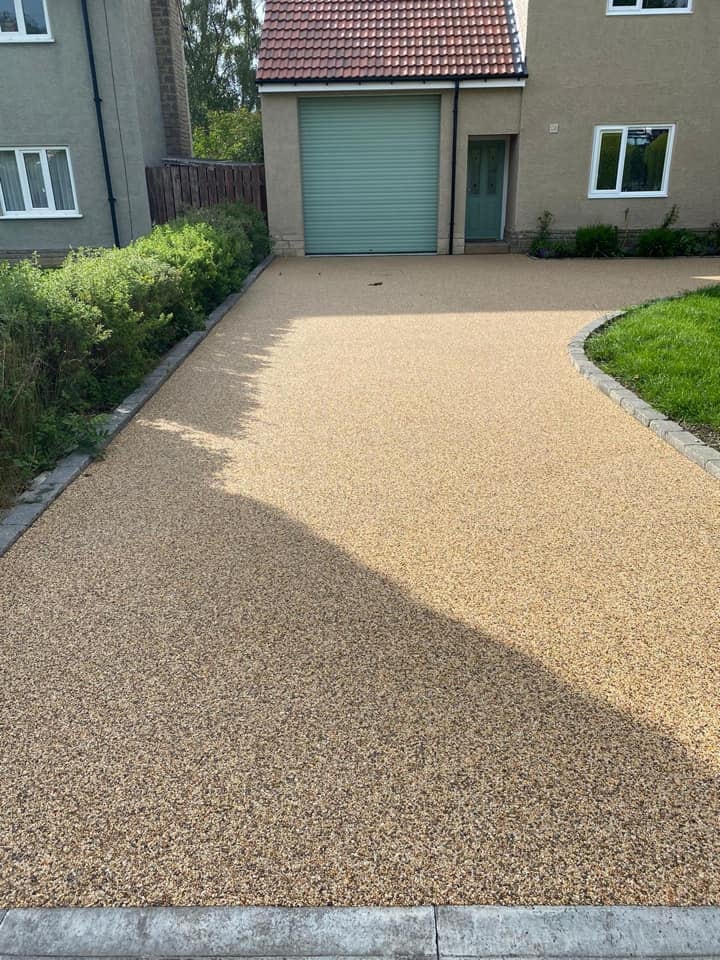 Golden resin driveway leading to a green garage door