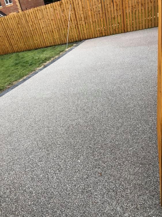 Light grey resin driveway bordered by timber fencing